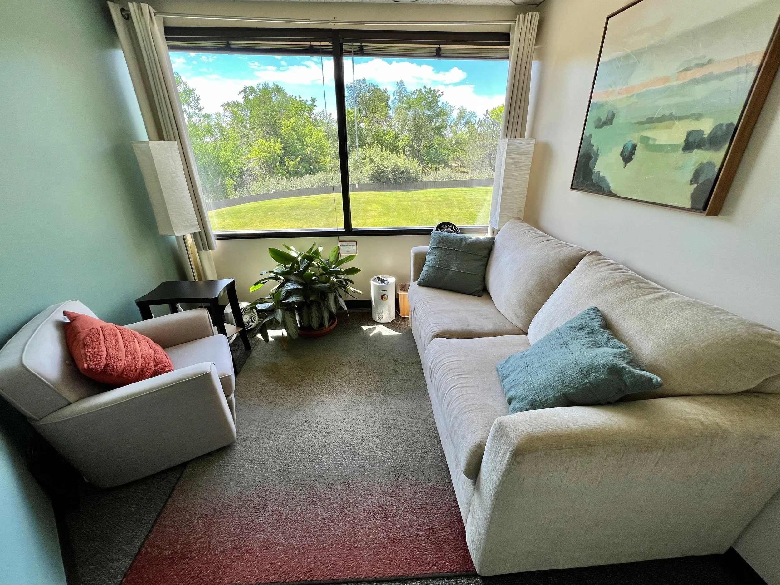 Cozy therapy room with sofa, armchair, plants, and natural light at Ashton Mental Health in Boulder, CO